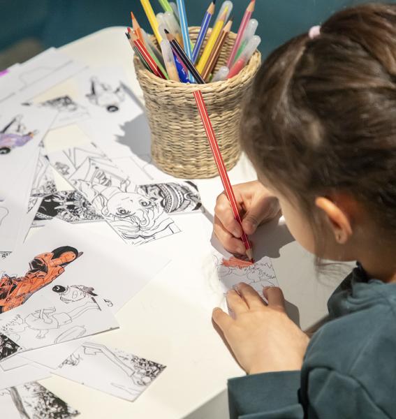 jeune visiteuse en train de colorier une image dans l'exposition Miyazaki