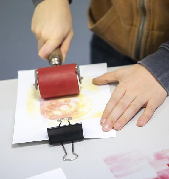 enfant en train d'utiliser un rouleau encré pour réaliser une image en estampage