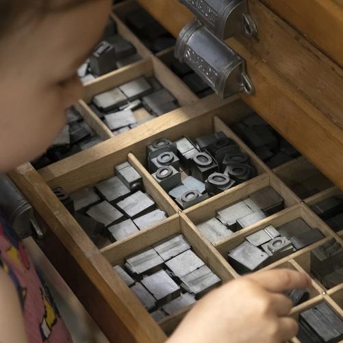 enfant qui tient un caractère mobile d'imprimerie issu d'une casse